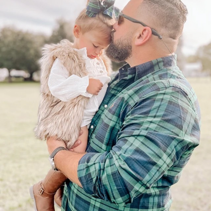 matching daddy and little girl, wearing navy blue and dark green plaid / black watch tartan shirt and hair bow