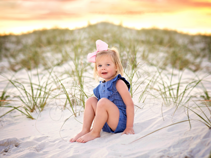 little girl on beach wearing hair bow and outfit