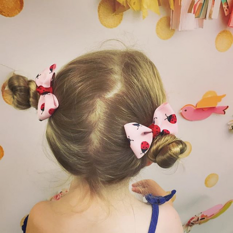 little girl wearing cute hair bow clips in her space buns