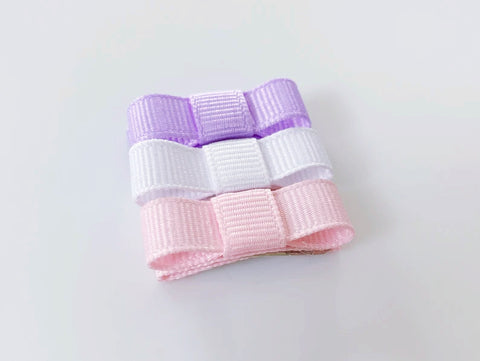 smallest baby hair bows for newborn infants in light pink, white, and lavender