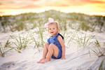 little girl on the grassy sand beach wearing a jumbo light pink hair bow
